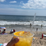 Holding a delicious cocktail overlooking a sunny beach day in Rhode Island