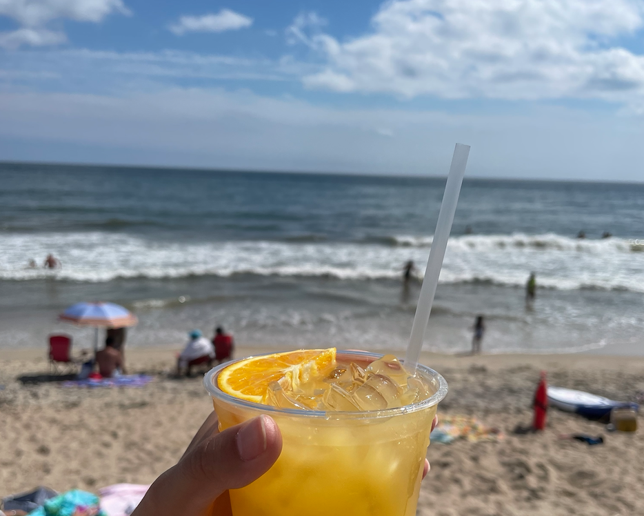 Holding a delicious cocktail overlooking a sunny beach day in Rhode Island